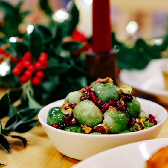 A bowl of dressed sprouts surrounded by winter foliage