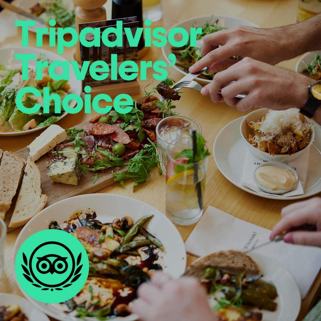 A table full of plates of food. Overlayed text reads Tripadvisor Travelors' Choice with a Tripadvisor logo