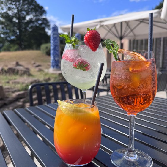 Three glasses of summer cocktails on an outdoor table.