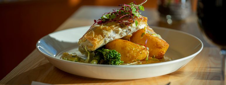 A plate of vegetables and pastries, on a table with cutlery