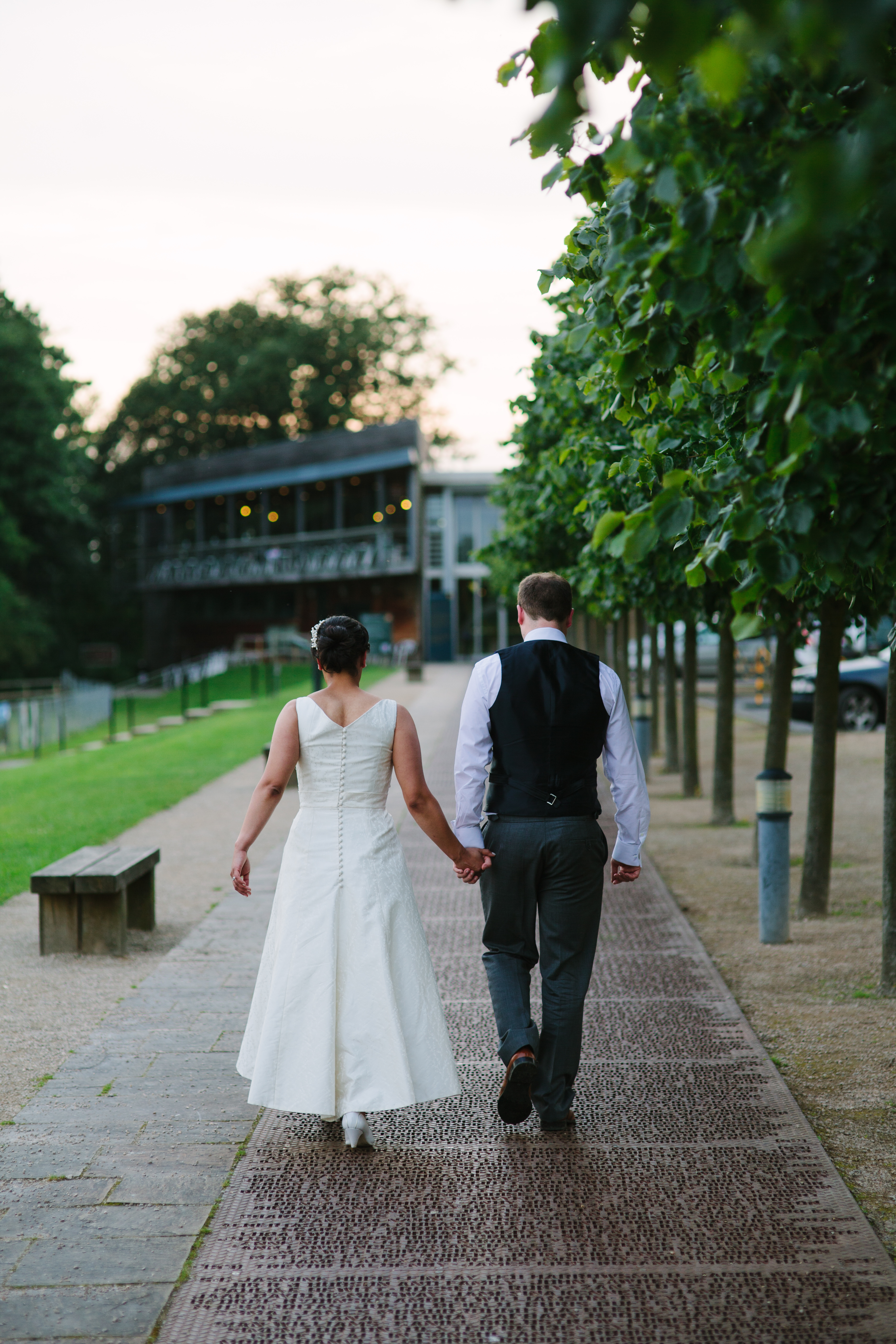 A bride and groom walking along a metal walkway covered in names, towards YSP Centre