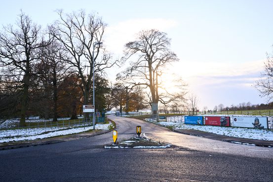 The main entrance road to YSP, with colourful posters attached to fencing and other signage.