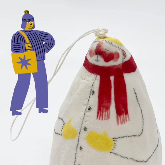 A porcelain bell ornament, painted to show a figure wearing a winter scarf
