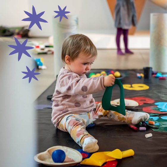 A child plays wit colourful objects in a gallery space.