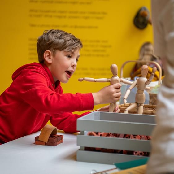 A child playing with a human figure mannequin.
