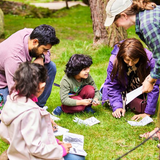 A group of adults and children drawing together outdoors