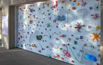 A white wall covered in colourful shaped objects and film screens.