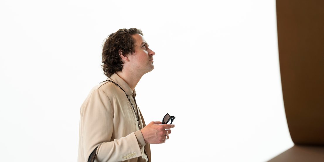 A man with a black designer bag, looking at a bronze sculpture.