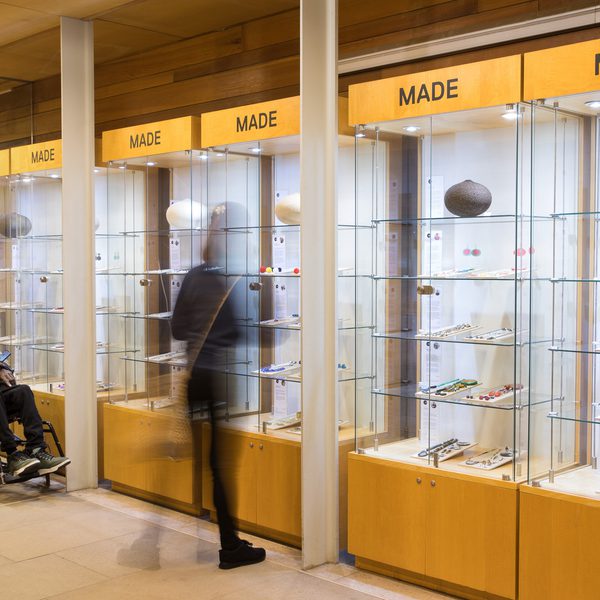 A group of people, including a wheelchair user, looking at jewellery and ceramics in glass fronted display cases.