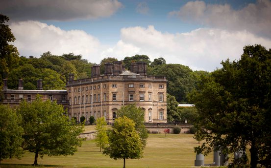 A large historic hall surrounded by trees.