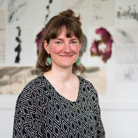 A woman with brown hair wearing a black geometric patterned top