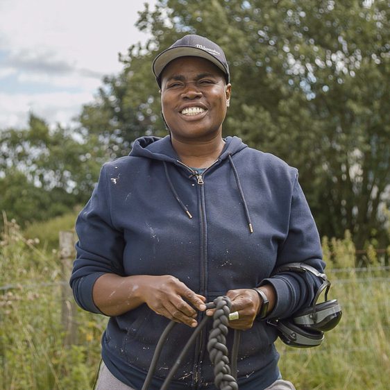 A black woman wearing a blue hoody, standing in a field at YSP