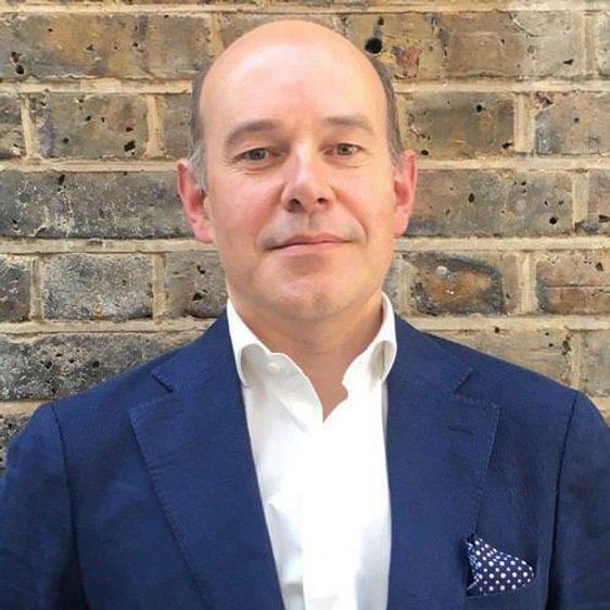 A white man wearing a blue suit and a white shirt