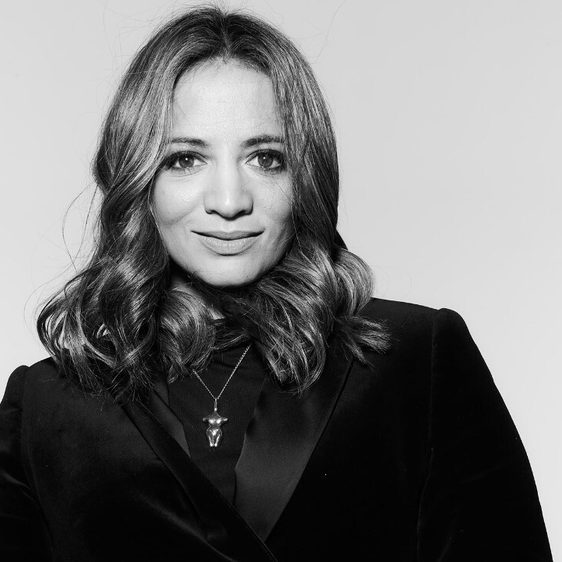 A black and white headshot of a woman with long dark hair.