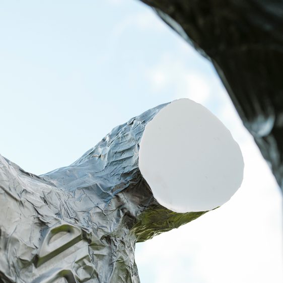 A close up of a silver figure with a flat featureless face