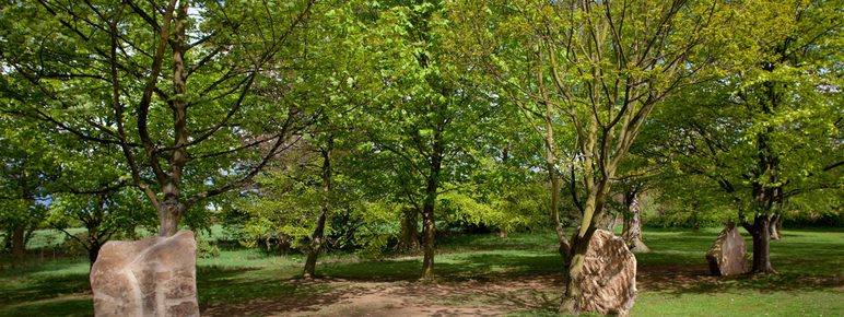 Three large stones, with trees growing behind them