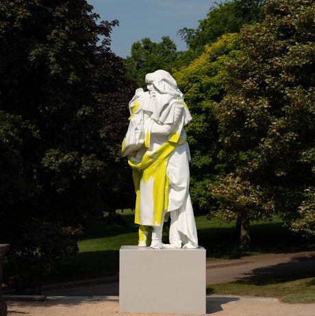 A yellow and white sculpture of a figure draped in clothing