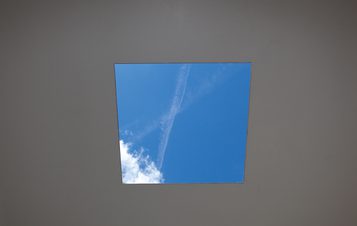 The view through a square hole in the roof of Skyspace, showing a blue sky with clouds and airplane trails