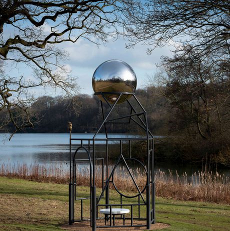 A metal frame sculpture with a silver ball at the top.