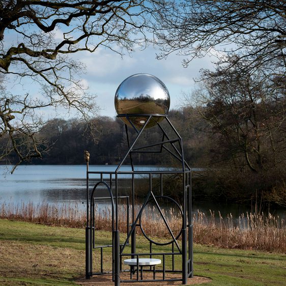 A metal frame sculpture with a silver ball at the top.
