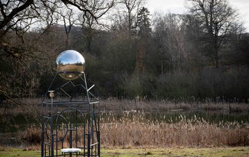 A metal frame sculpture with a silver ball at the top.