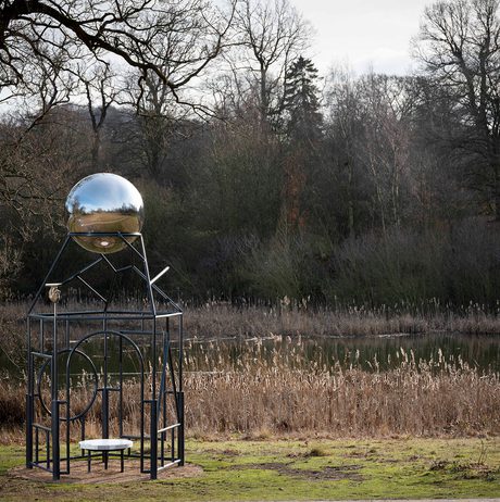 A metal frame sculpture with a silver ball at the top.