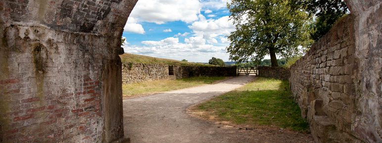 The view from a brick archway out over the countryside with a blue, cloudy sky