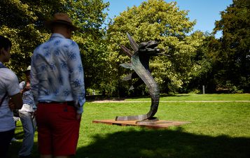 people looking at a 3 headed snake sculpture outdoors