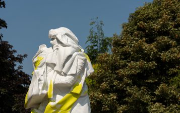 A yellow and white sculpture of a figure draped in clothing