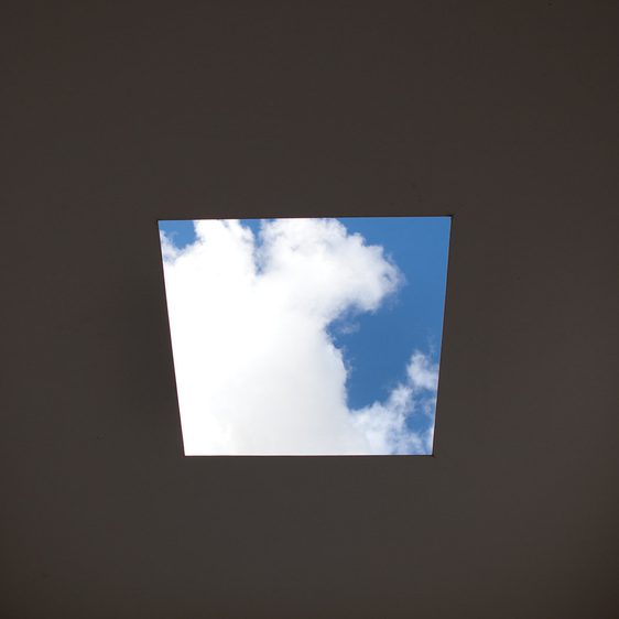 The view through a square hole in the roof of Skyspace, showing a blue sky with clouds.