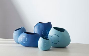 A collection of blue ceramic vessels displayed on a white surface