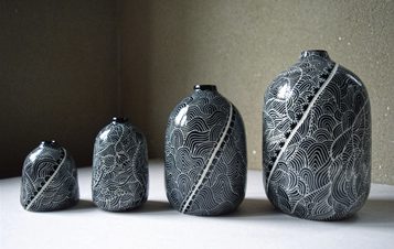 Four intricately patterned dark blue and white porcelain vases, displayed in a row increasing in size from left to right.