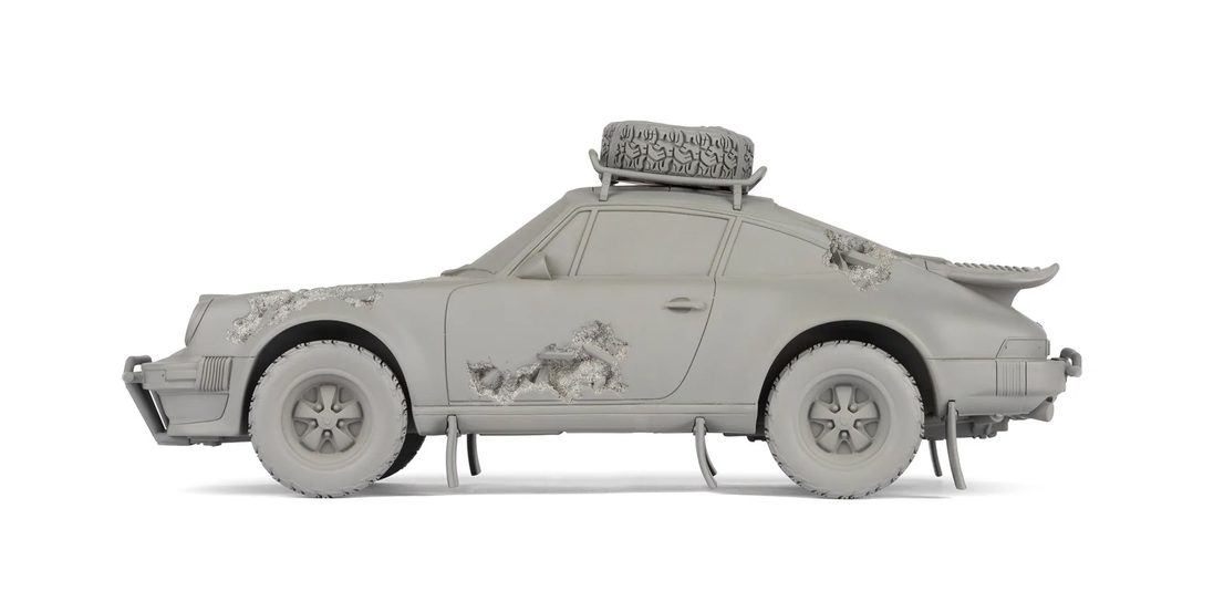 A sculpture of a grey car with eroded crystal sections.