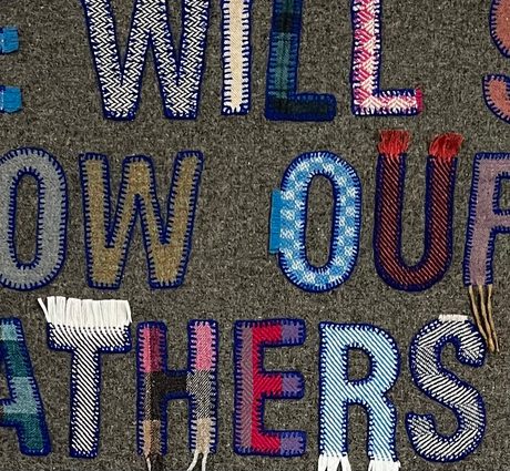 Detail of a fabric banner with letters made from reclaimed textiles.