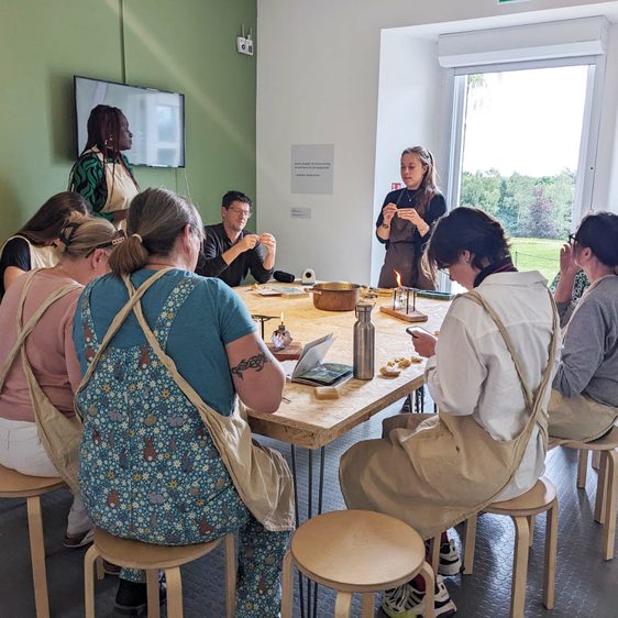 A group of people sitting around a table making animals out of wax