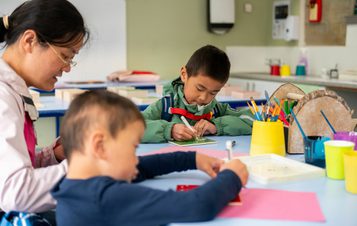 A family drawing on paper at a table