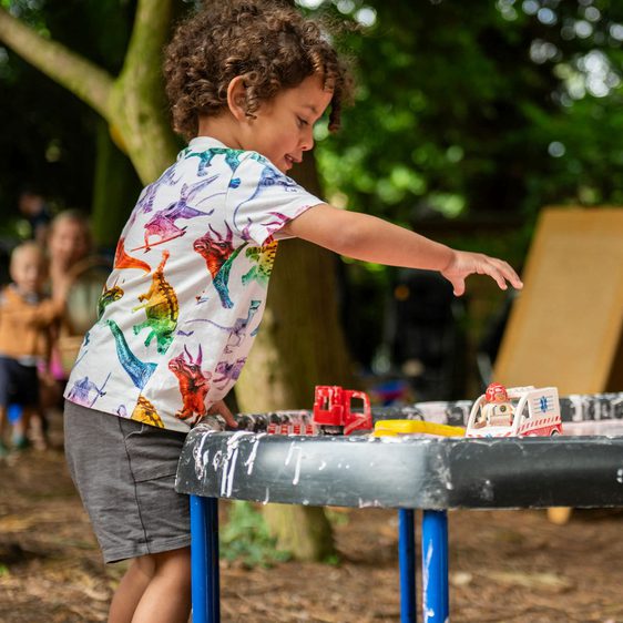 A child playing with cups on a messy outdoor table