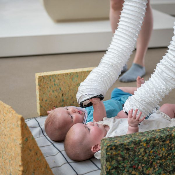 Two babies playing with long white tubes