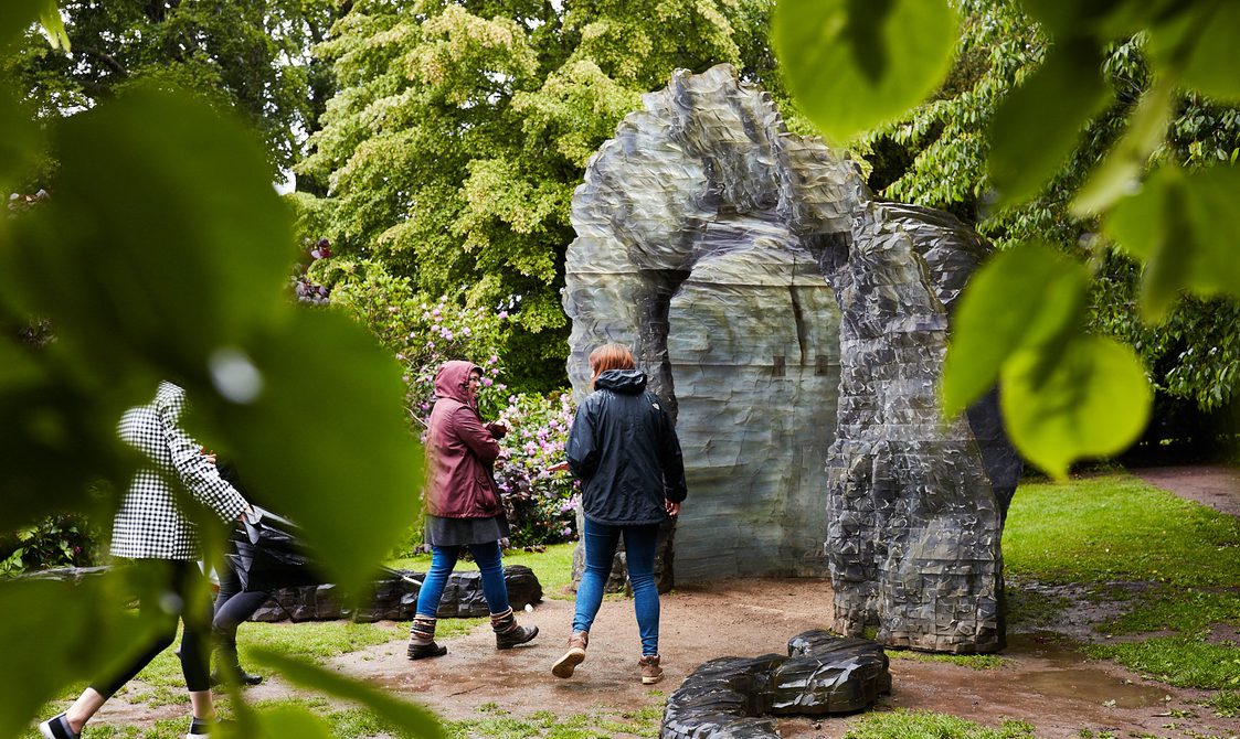 Three people in rain coats looking at an igloo-like sculpture