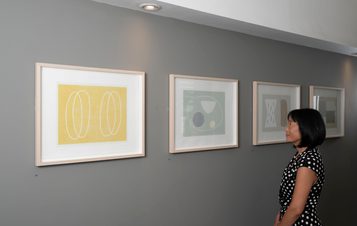 A woman looking at a wall of framed prints
