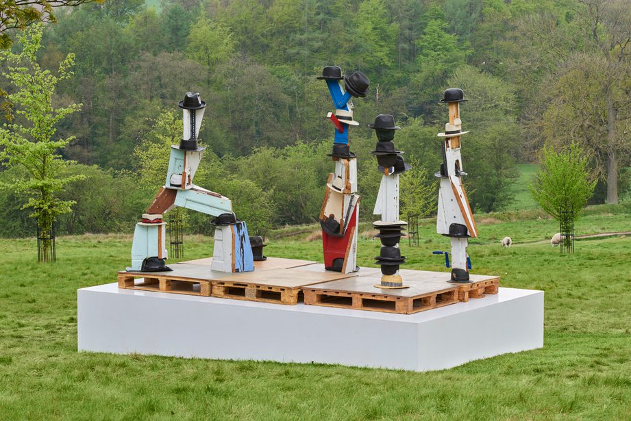 Four sculptures with fedora, boater and trilby hats resting on top.
