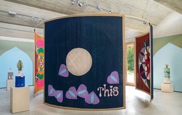 A series of fabric hangings in the centre of a gallery space.