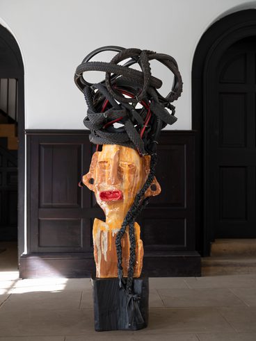An orange ceramic figure with 'hair' made from rubber bicycle tyres.