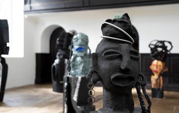 A collection of carved wood and ceramic figures in a gallery.