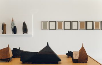 A display of carved wooden houses and drawings.