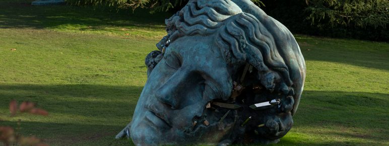 A large bronze sculpture of a woman's head, with eroded crystal sections.
