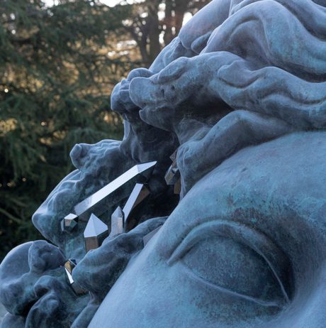 A close up of a bronze head sculpture with eroded crystallised sections.