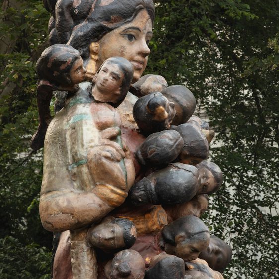 A sculpture of a woman, covered in a chain of heads.