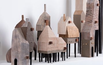 Multiple miniature handcrafted houses on a shelf.