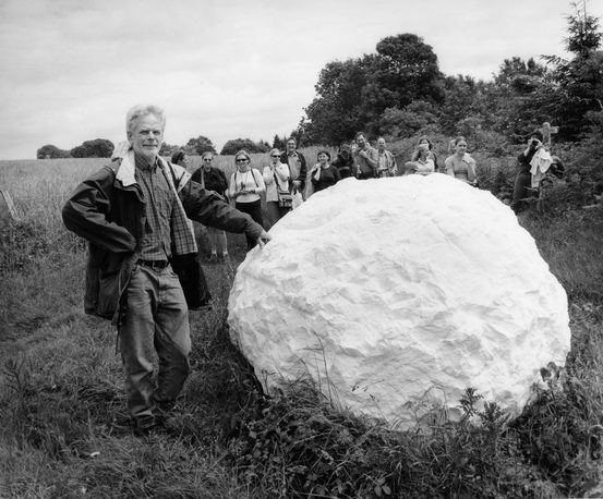 The artist Andy Goldsworthy standing next to a giant white snowball